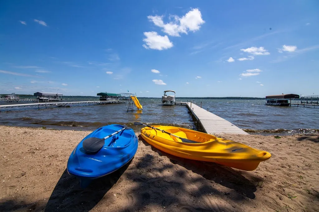 Blue and yellow kayaks resting on the sandy beach at the water's edge