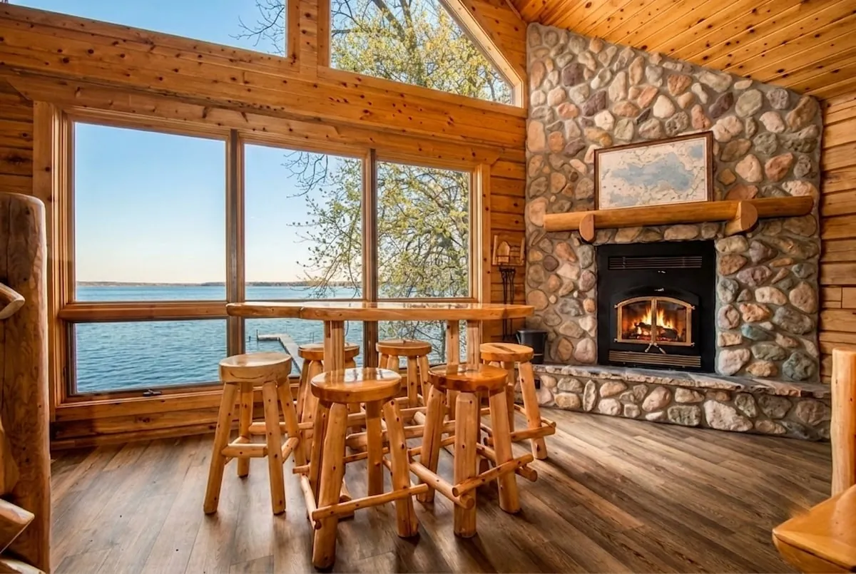 Log dining table set beside the stone fireplace with warm cabin lighting