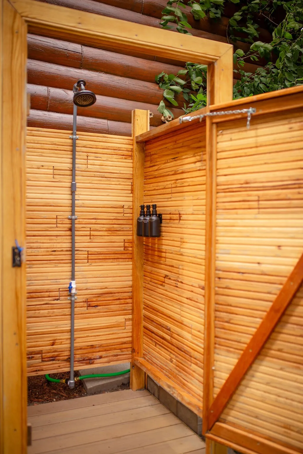Private outdoor cedar shower with rainfall shower head near the cabin