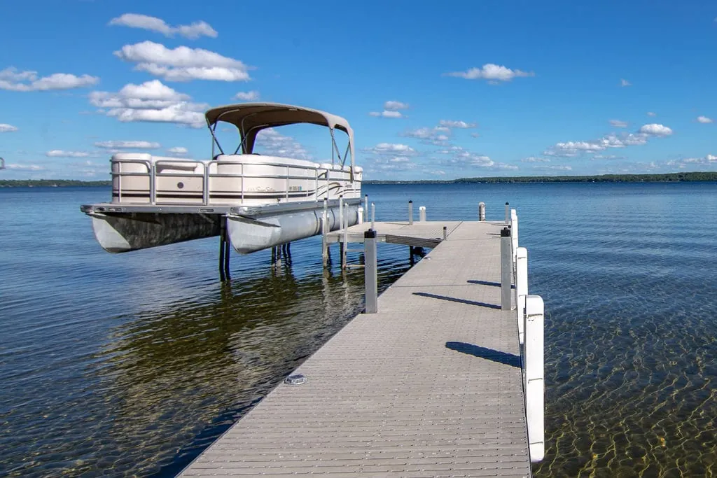Pontoon boat tied to the private dock on calm Lake Miltona water
