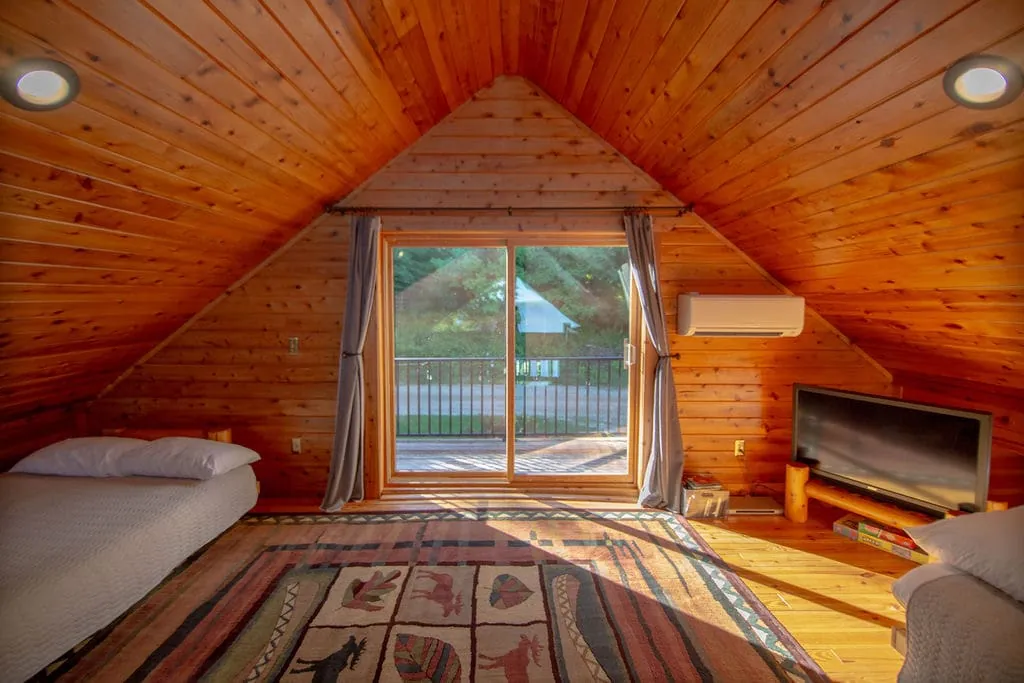 Loft bedroom with bed, TV, and sliding door to the private balcony