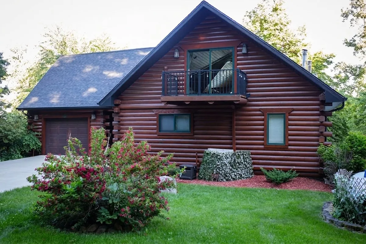 Log cabin front exterior with manicured lawn and landscaped entry